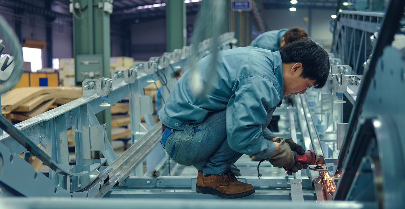 Workers in the polished escalator parts, Zhejiang, China. Source. ILO Flickr / https://t.ly/MtAqr